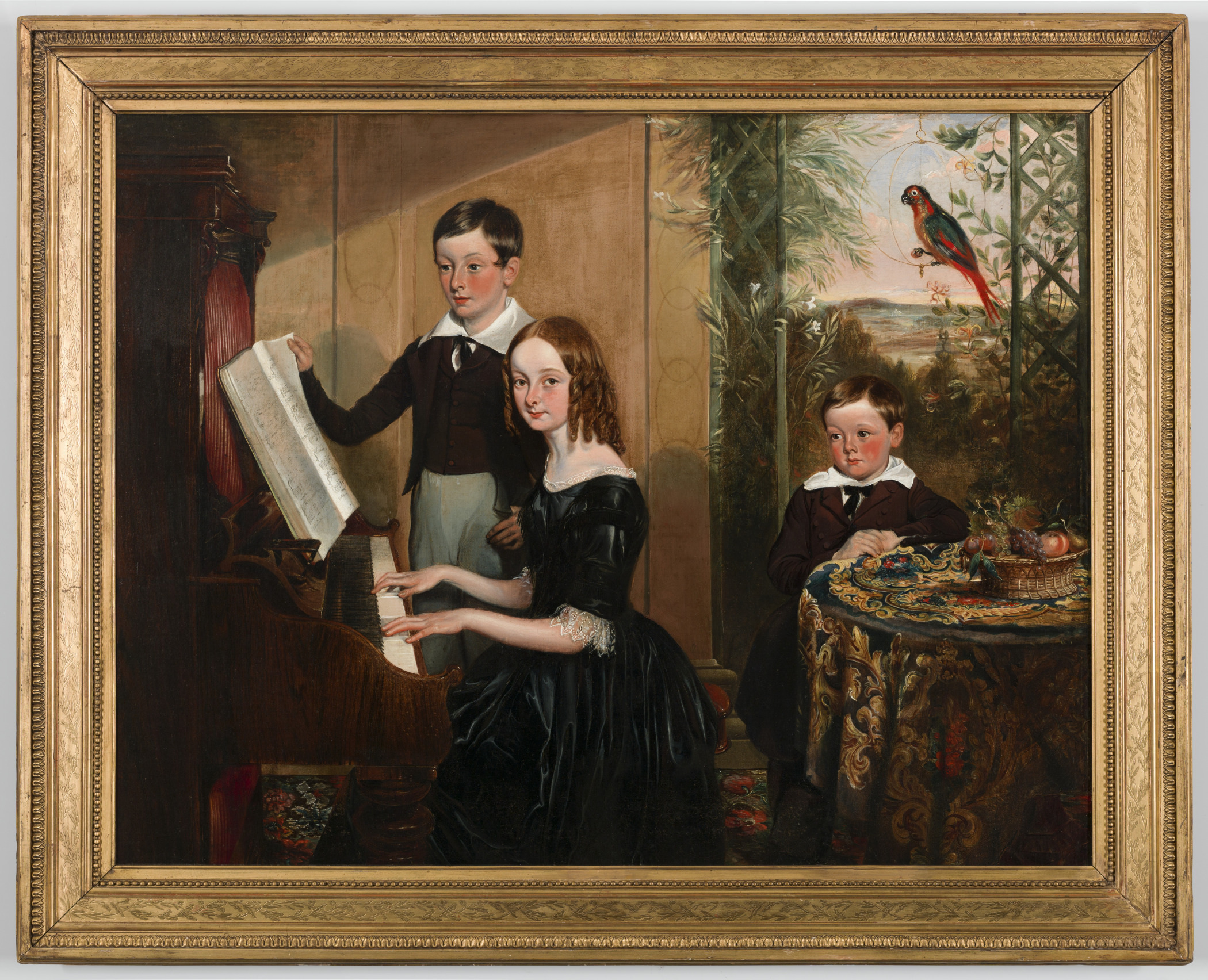 A framed painting depicts three children indoors. A girl in a black dress plays a piano, a boy stands beside her holding sheet music, and another boy sits at a table with fruit. A parrot perches above. A lush outdoor scene is visible through a window.