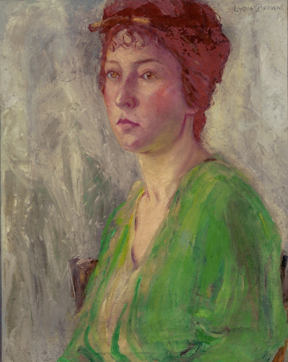 Portrait of a person with curly auburn hair wearing a vivid green blouse. The background is a mix of muted grays and greens, and the subject gazes to the side with a neutral expression.