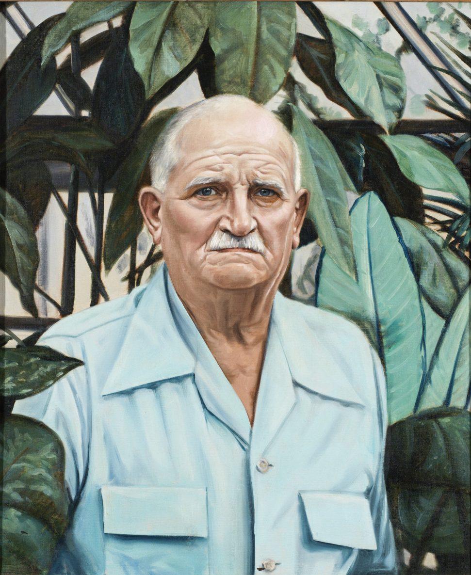A serious-looking older man with a mustache is wearing a light blue shirt. He stands in front of large green leaves, creating a lush background. His expression is stern, and the painting captures detailed features and textures.