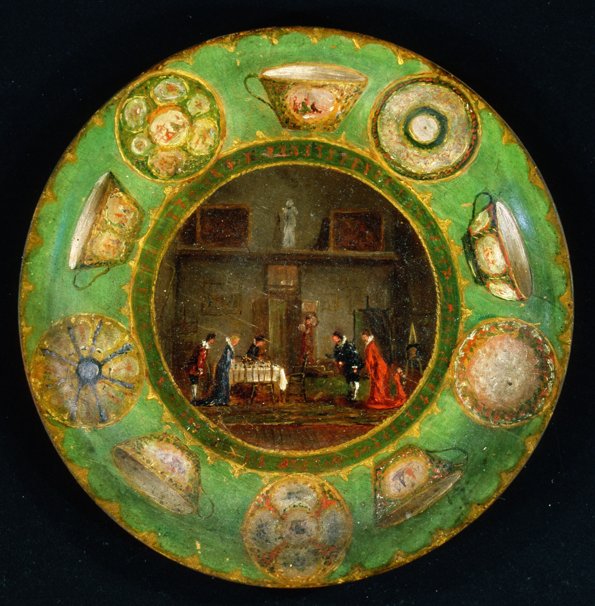 A circular painting depicting a domestic scene with people gathered around a table inside a room. The border features various decorative teacups and saucers on a green background.