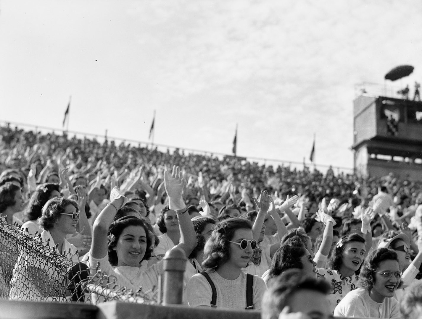 A black and white photo of young women cheering in the stands of Tiger Stadium.