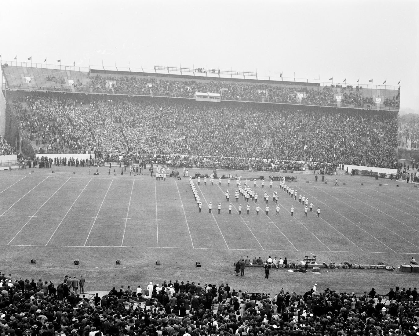 A wide shot of a marching band in formation on a football field.