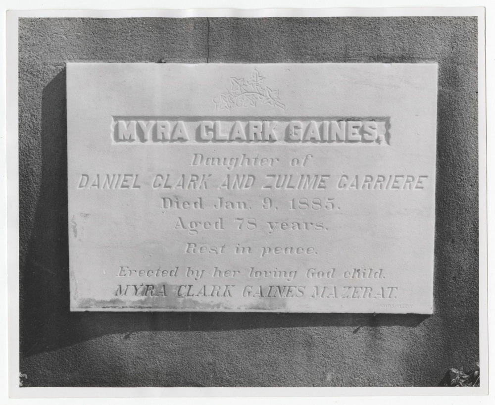 A black and white photo of a gravestone with the inscription: Myra Clark Gaines, Daughter of Daniel Clark and Zulime Carriere. Died Jan. 9, 1885. Aged 78 years. Rest in peace. Erected by her loving God Child, Myra Clark Gaines Mazerat.