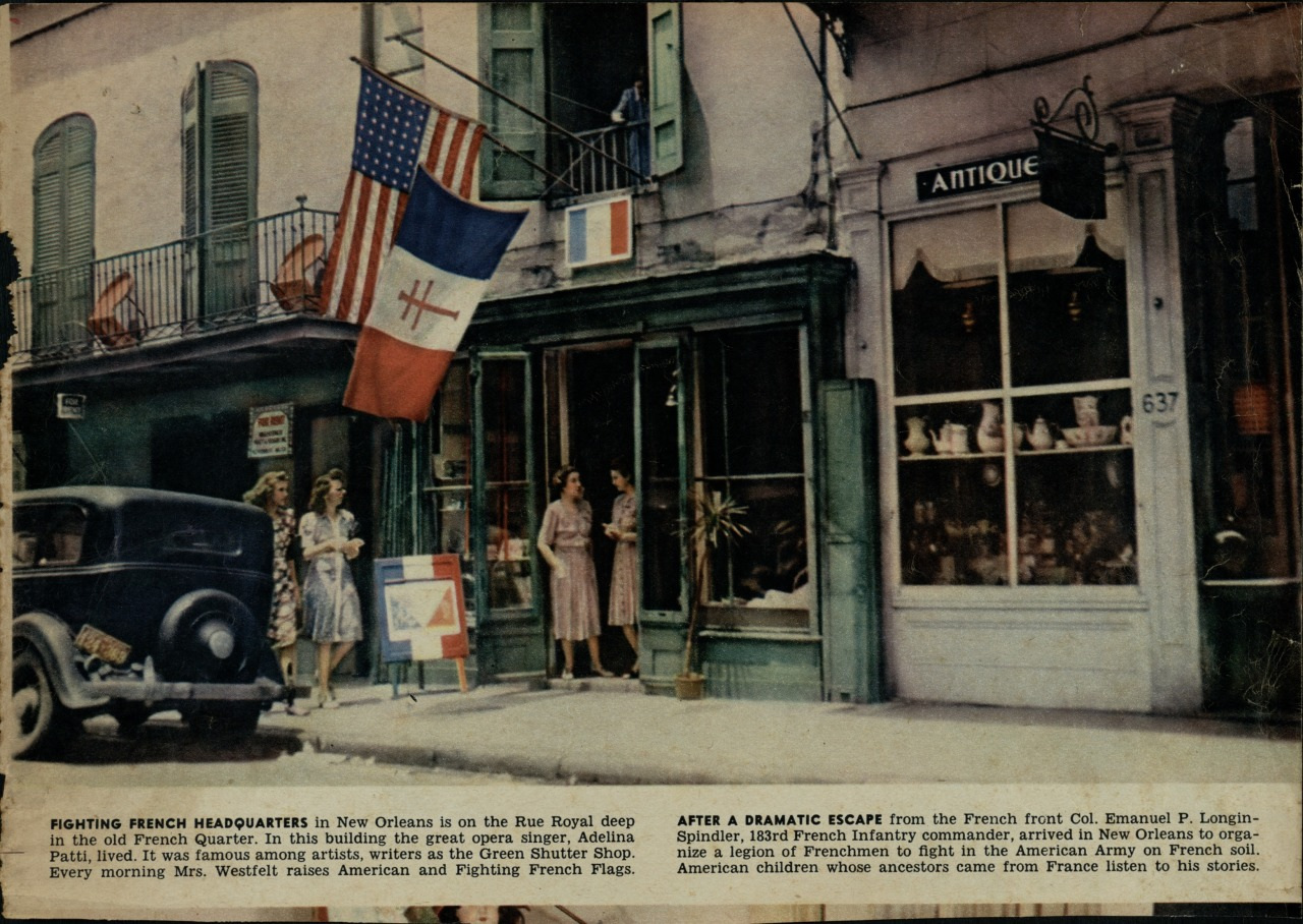 A vintage photo of a street in New Orleans shows the Fighting French Headquarters, draped with French and U.S. flags. A classic car is parked on the street, and pedestrians walk by, including a soldier in uniform near the entrance of a building.