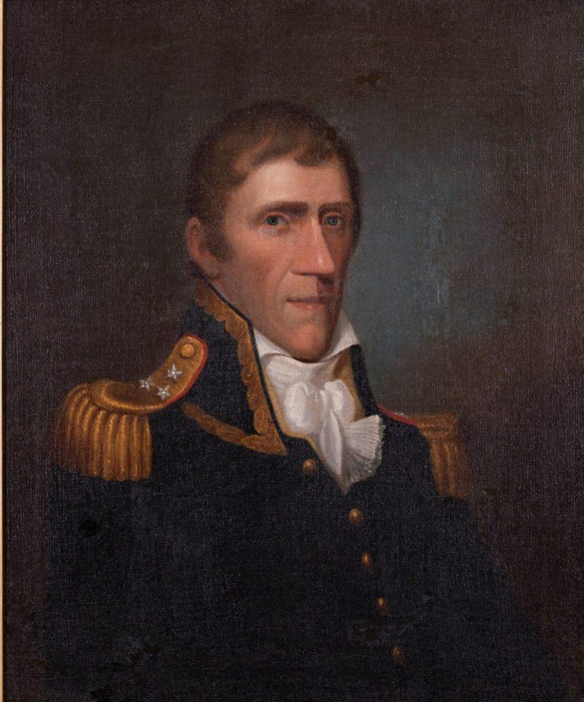 A formal portrait of a man in military attire, featuring a dark coat with gold epaulettes and buttons. He has short hair and wears a white cravat. The background is dark, highlighting the subject.