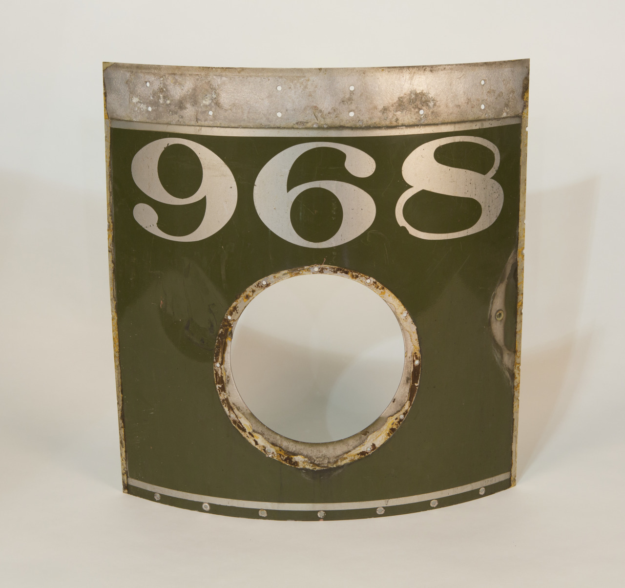 A rectangular metal panel with the number 968 in large, bold numerals on a green background. The panel has a circular cutout in the center and shows signs of wear.
