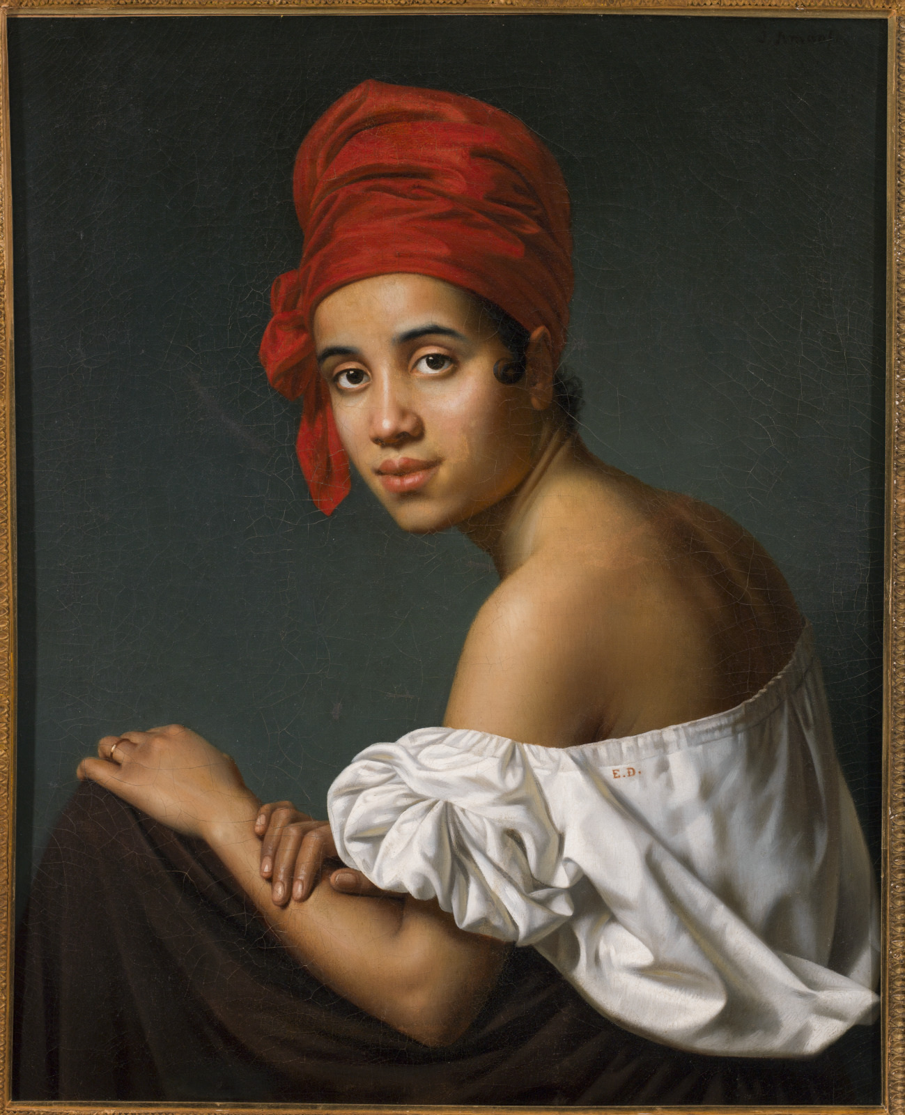 Portrait of a woman with a neutral expression, wearing a red headscarf, a white off-the-shoulder top, and a brown skirt. She sits against a dark background, her gaze directed at the viewer.