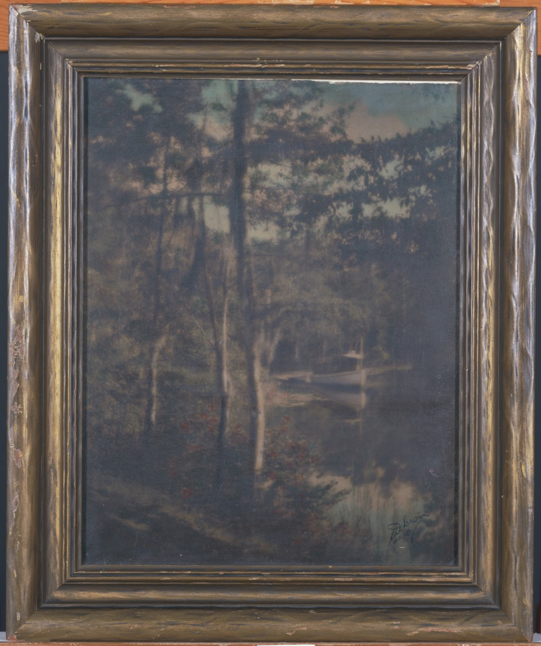An impressionistic painting of a wooded landscape with tall trees and a serene body of water, framed in an ornate, dark wooden frame. The scene has a soft focus, evoking a tranquil and dreamlike atmosphere.