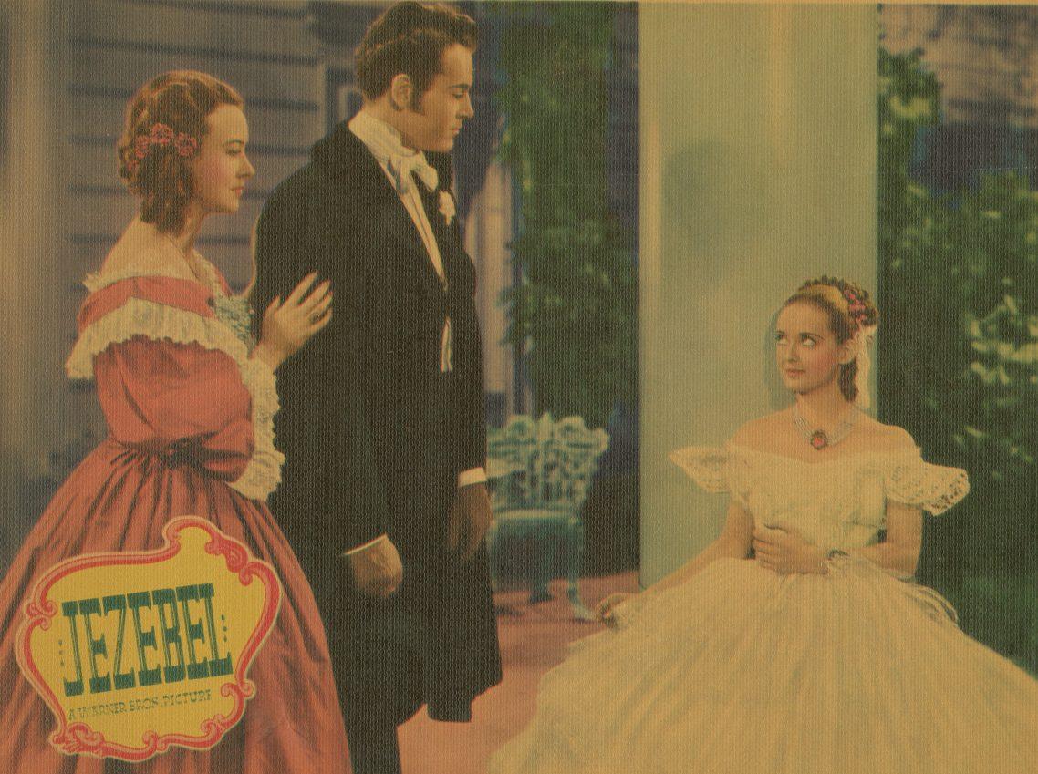 A vintage poster of the film Jezebel features three actors in elegant period costumes. A man in a black suit stands between two women, one in a red dress and the other in a white gown, set against a ballroom background.