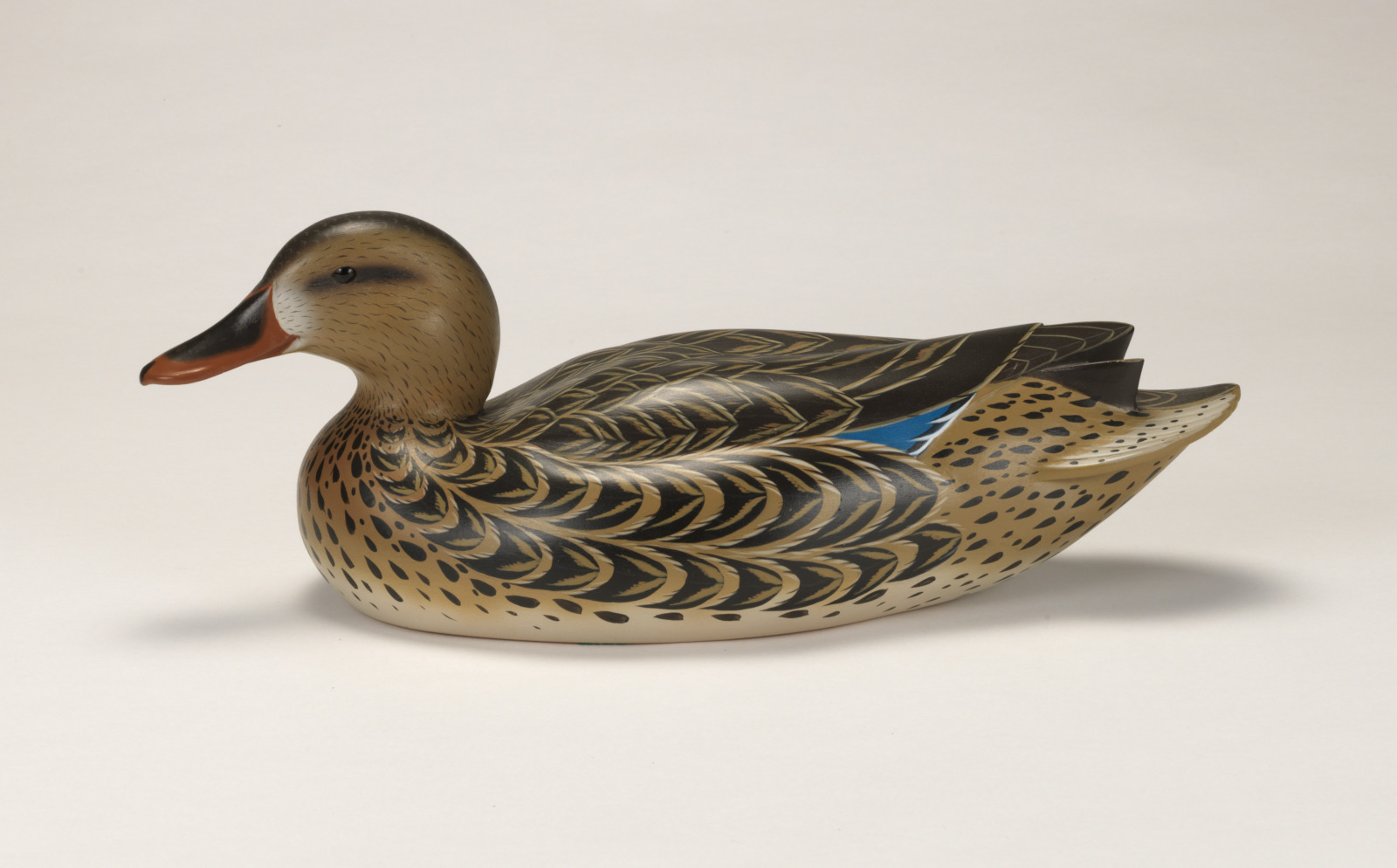 A realistic carving of a mallard duck depicted as if floating on water.