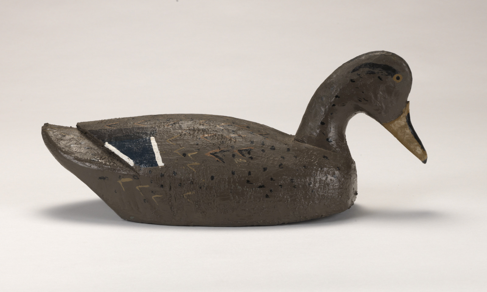 A realistic carving of a mallard duck depicted as if floating on water.