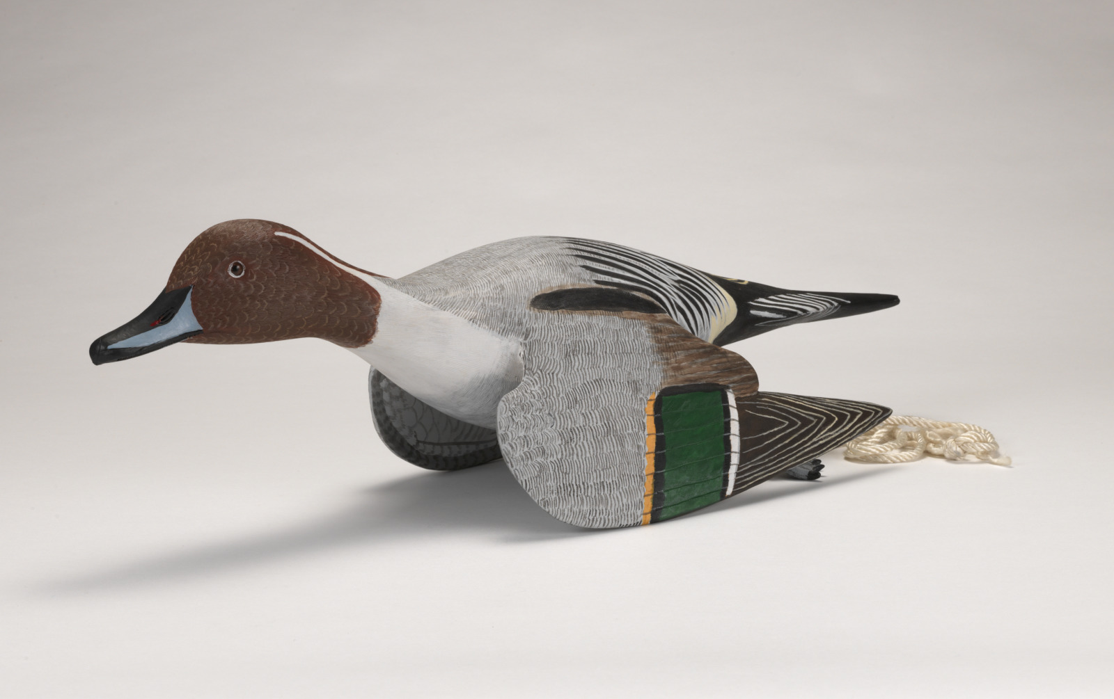 A realistic carving of a pintail drake duck depicted as if taking off from water.