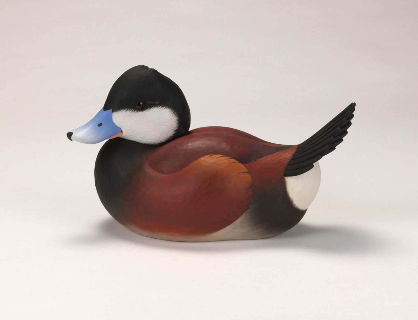 A realistic carving of a ruddy duck depicted as if floating on water.