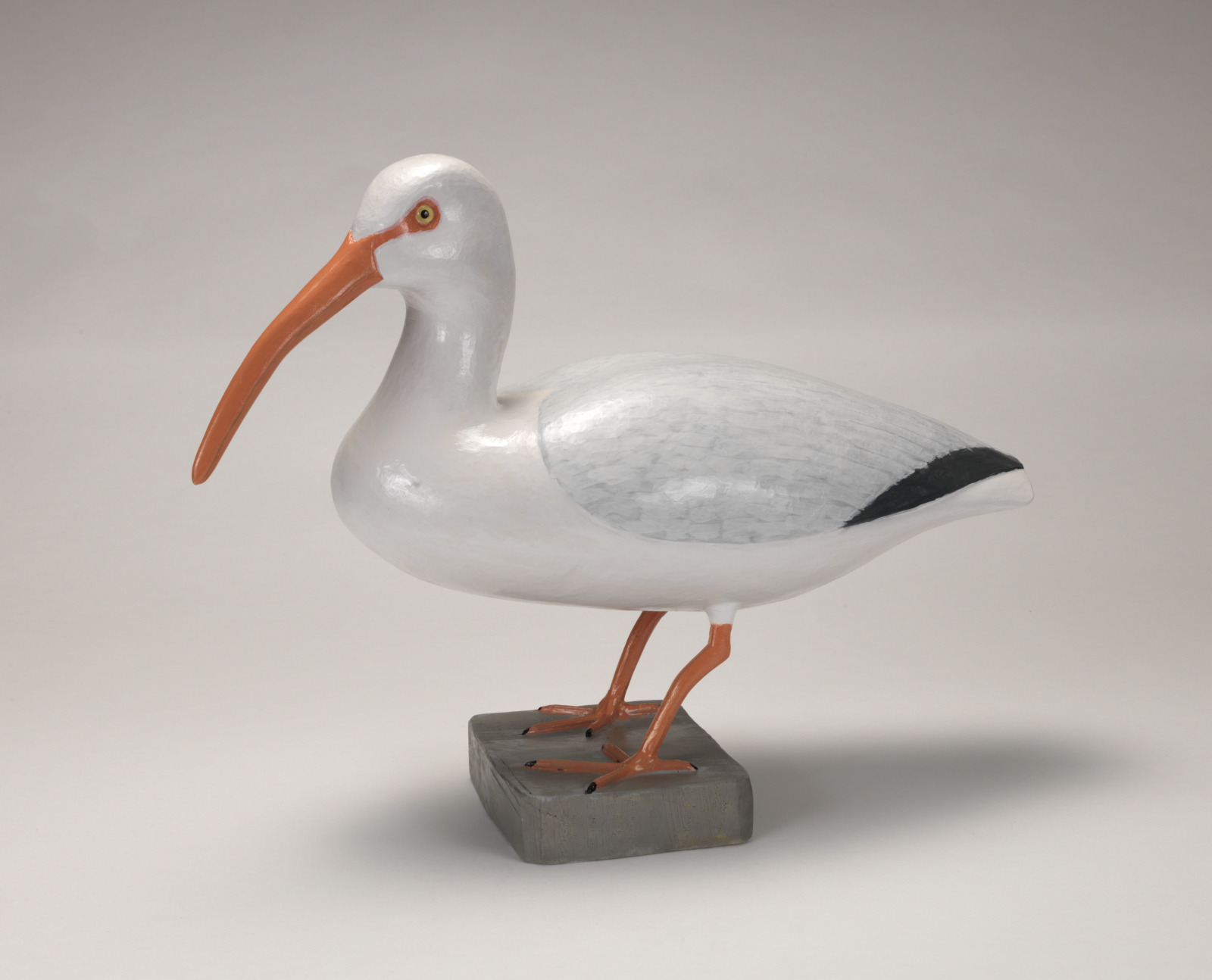 A realistic carving of an Ibis bird standing on a short pedestal.
