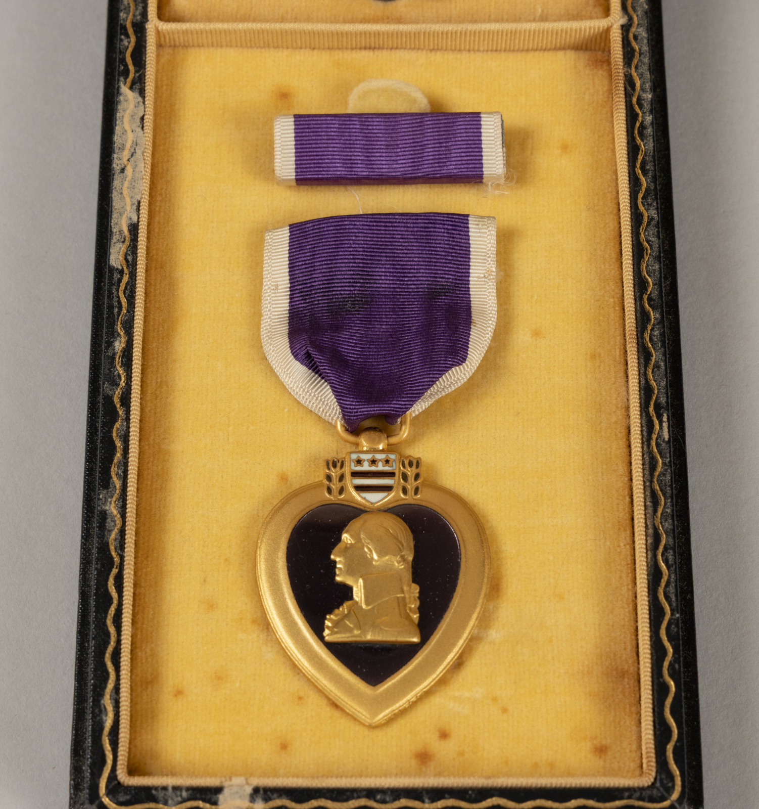 A photograph of Cervantes’s Purple Heart contained in a small display box with yellow liner.