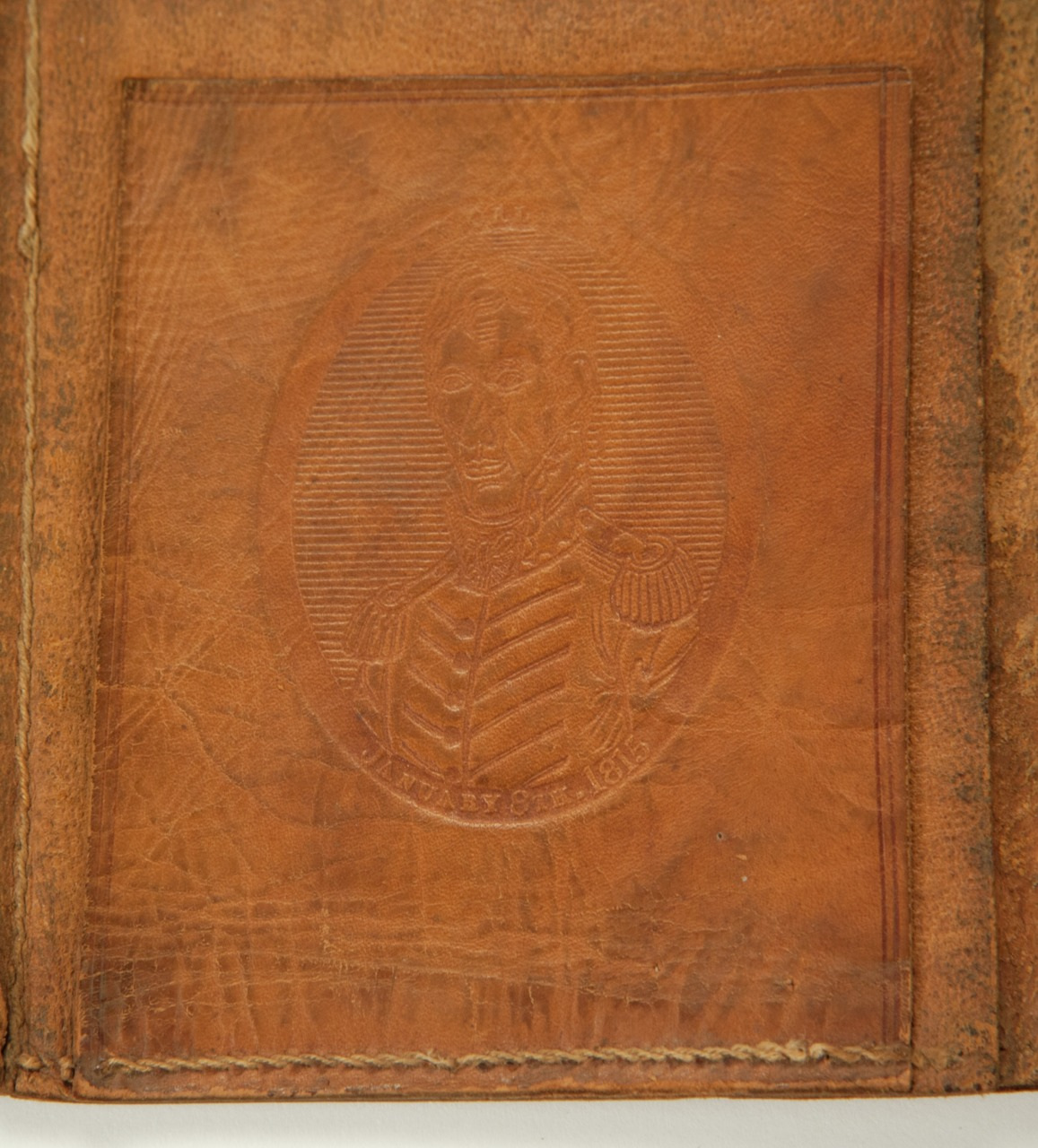 A worn leather surface features an embossed image of a man in an old-fashioned military uniform. The text February 15 is partially visible at the bottom of the design. The leather shows signs of aging and wear.