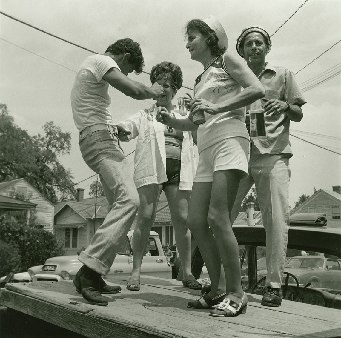 A group of people dance on a pickup truck bed while attending a crawfish festival in Louisiana.