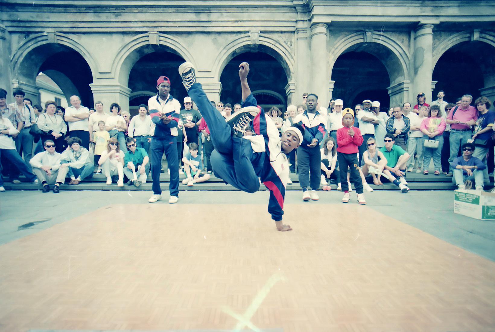 Breakdancers performing in Jackson Square in 1990 with spectators watching in the background.