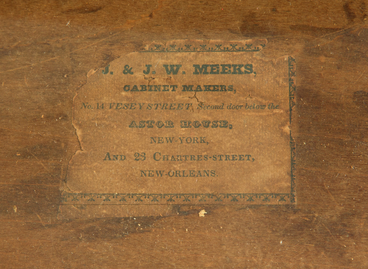 A worn, brown label with ornate green text reads: J. & J. W. Meeks, Cabinet Makers, No. 14 Vesey Street, second door below the Astor House, New-York, and 23 Chartres-Street, New-Orleans. The label is aged, with torn edges and faded print.