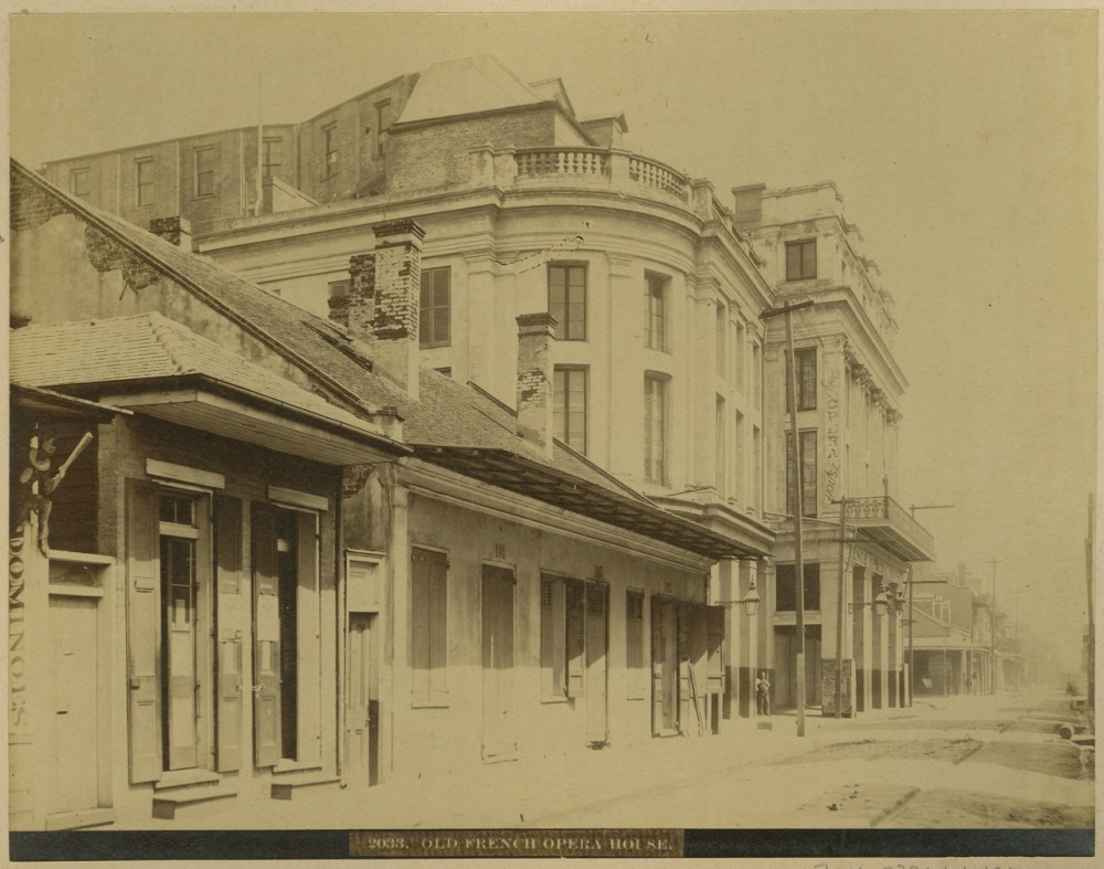 A sepia-toned historical photograph shows the exterior of the Old French Opera House with neighboring buildings. The street is empty, revealing architectural details and shuttered windows, capturing a quiet moment in the past. Text at the bottom reads 9836. OLD FRENCH OPERA HOUSE.