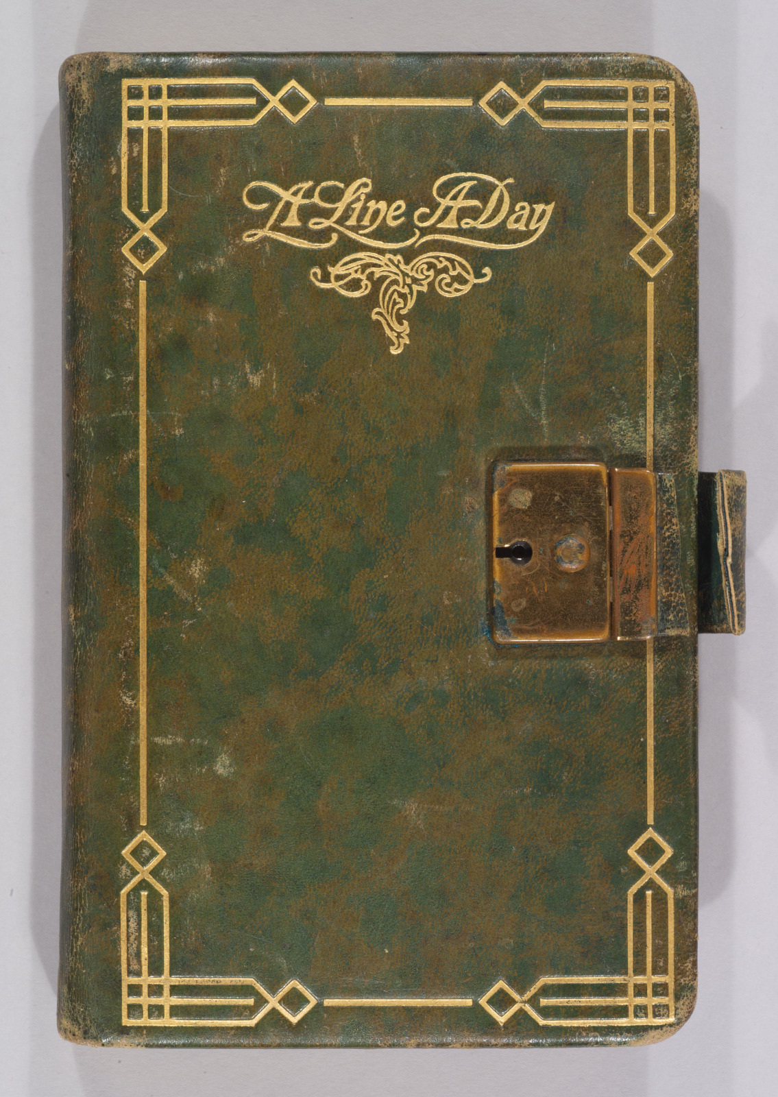 Green leather diary with a gold border and a locking clasp. The cover features ornate text that reads A Line A Day.