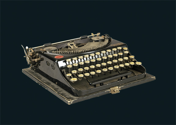 A vintage black typewriter with round white keys and a dark background.