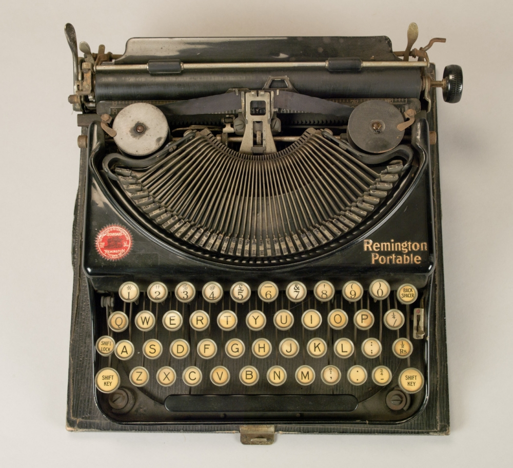 An antique Remington Portable typewriter with round keys and a black body, displayed on a plain background.