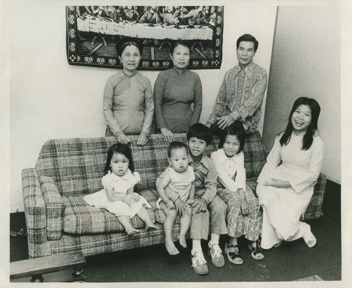 A vintage black and white photo shows a Vietnamese refugee family in their home in New Orleans, taken in 1979.