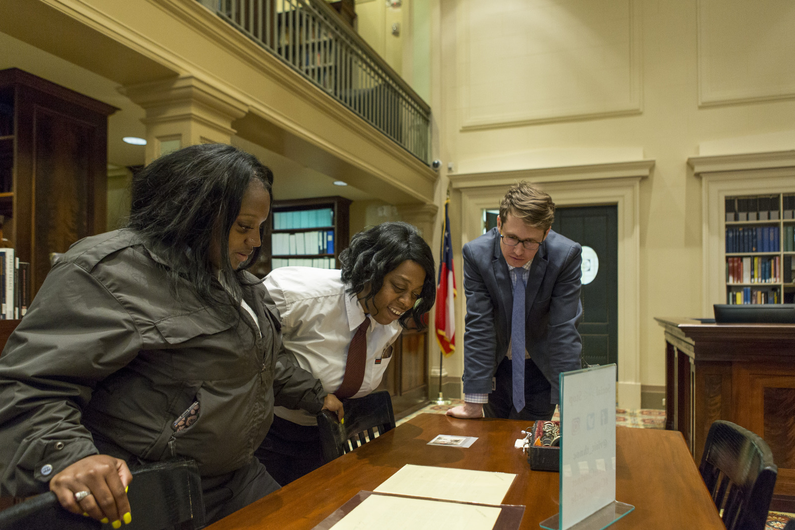 Two women view a historic document with a historian in WRC's reading room.