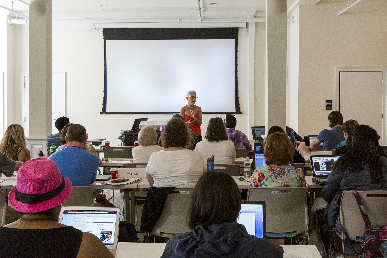 Educators participate in an Educator Open House event at HNOC. Teachers sit at desks in a classrom while listening to a faciliator.