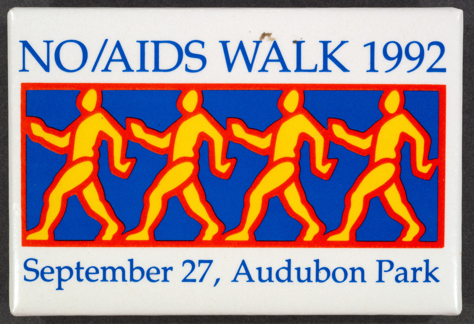 Image of a 1992 NO/AIDS Walk badge featuring a design of five stylized human figures in yellow and red on a blue background. The text reads NO/AIDS WALK 1992 and September 27, Audubon Park.
