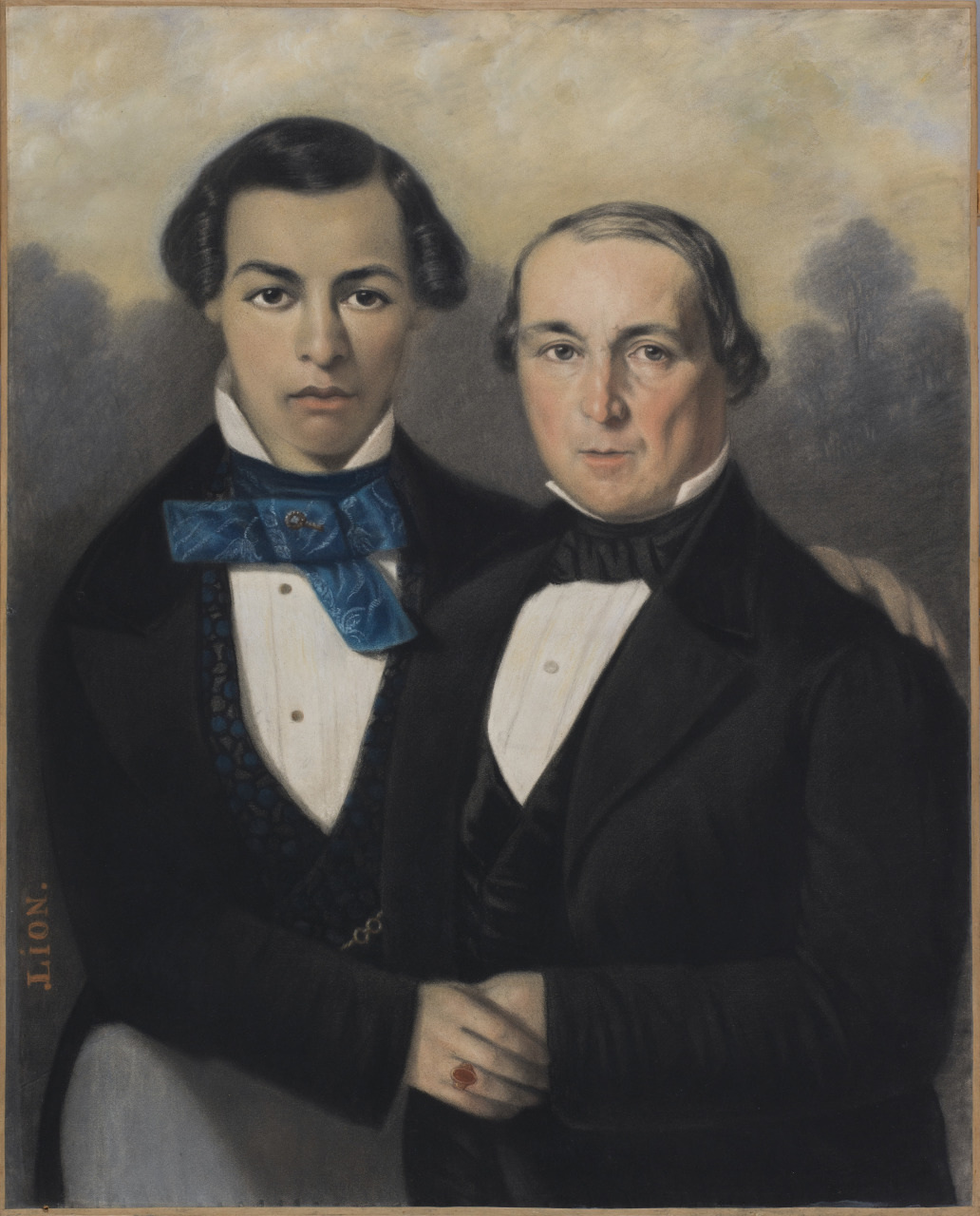 A vintage portrait of two men in formal 19th-century attire. The man on the left wears a dark suit with a blue cravat, while the man on the right is in a black suit with a white shirt. They stand close together against a muted, cloudy background.
