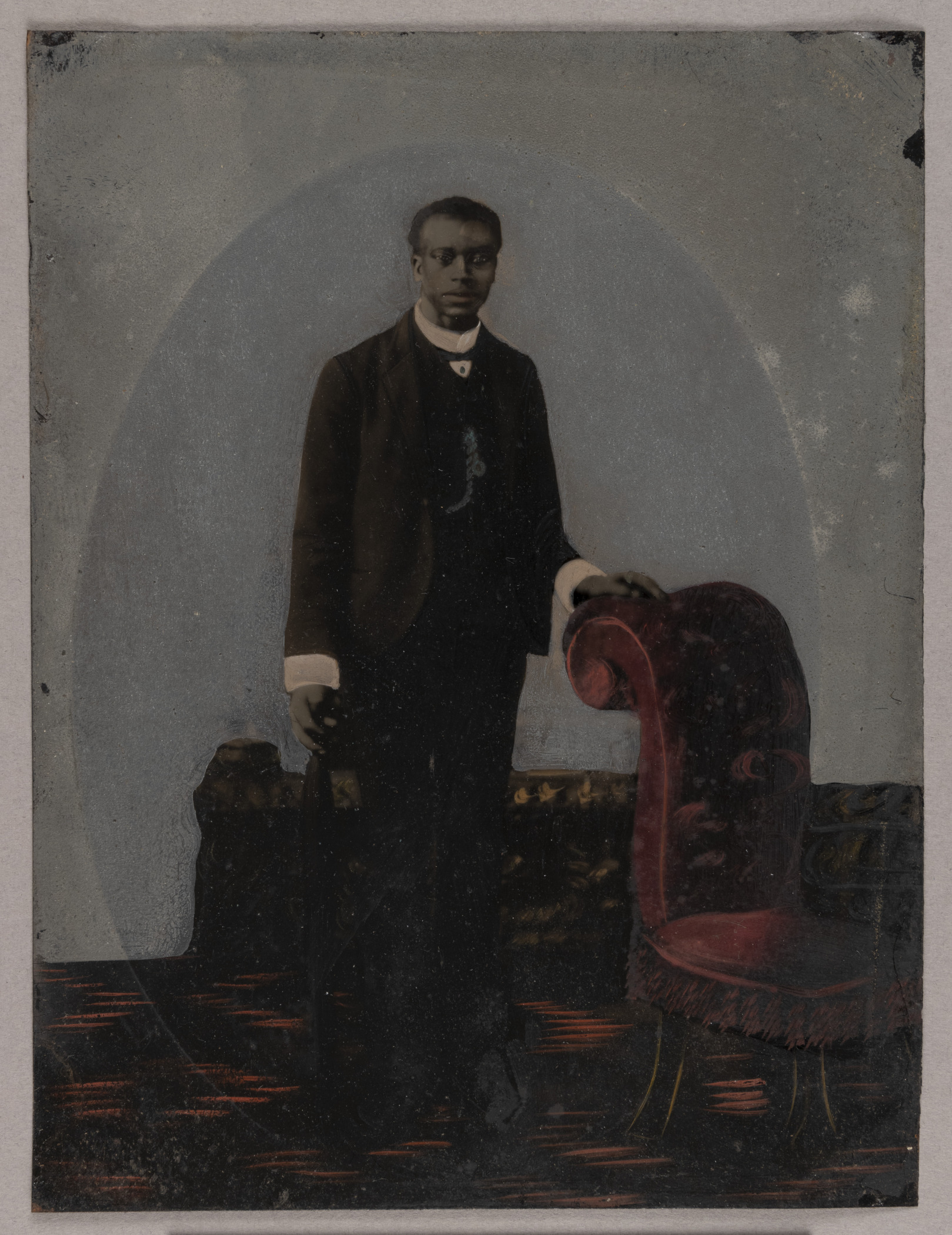 A tintype photograph shows the portrait of an unidentified member of the Jones family, mid-19th century posting next to an armchair.