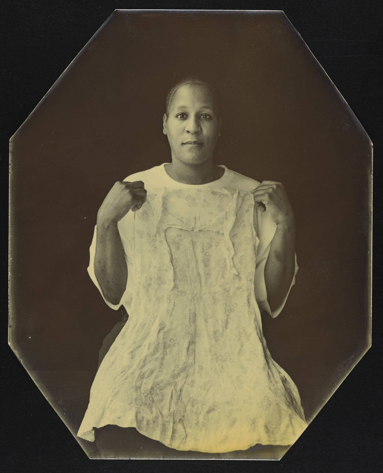 A sepia tone portrait printed on metal shows a middle aged black woman in a white dress.