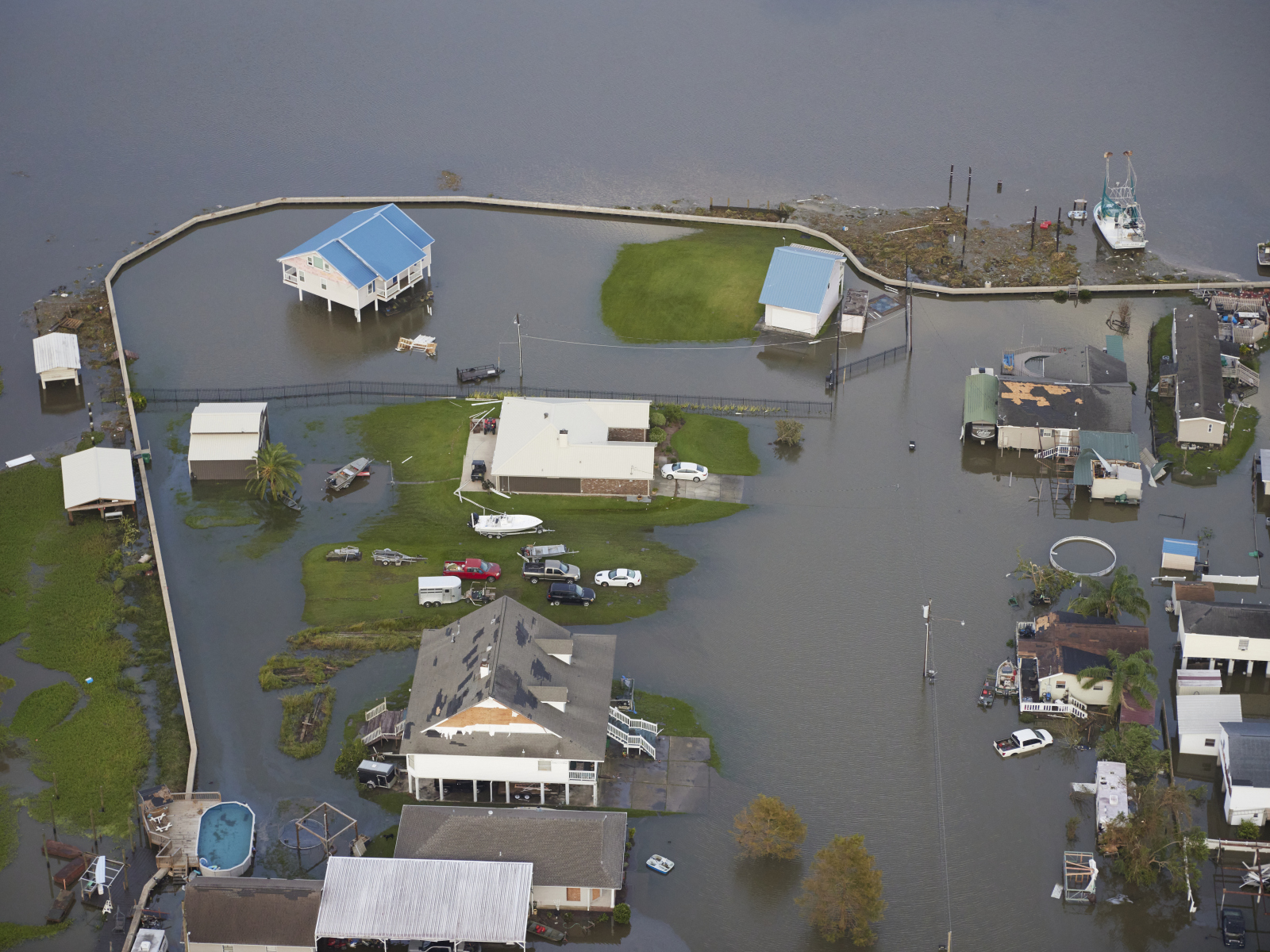 An aerial photo shows flooding in Lafitte after Hurricane Ida. A thin floodwall, which has been breached, is visible around the village.