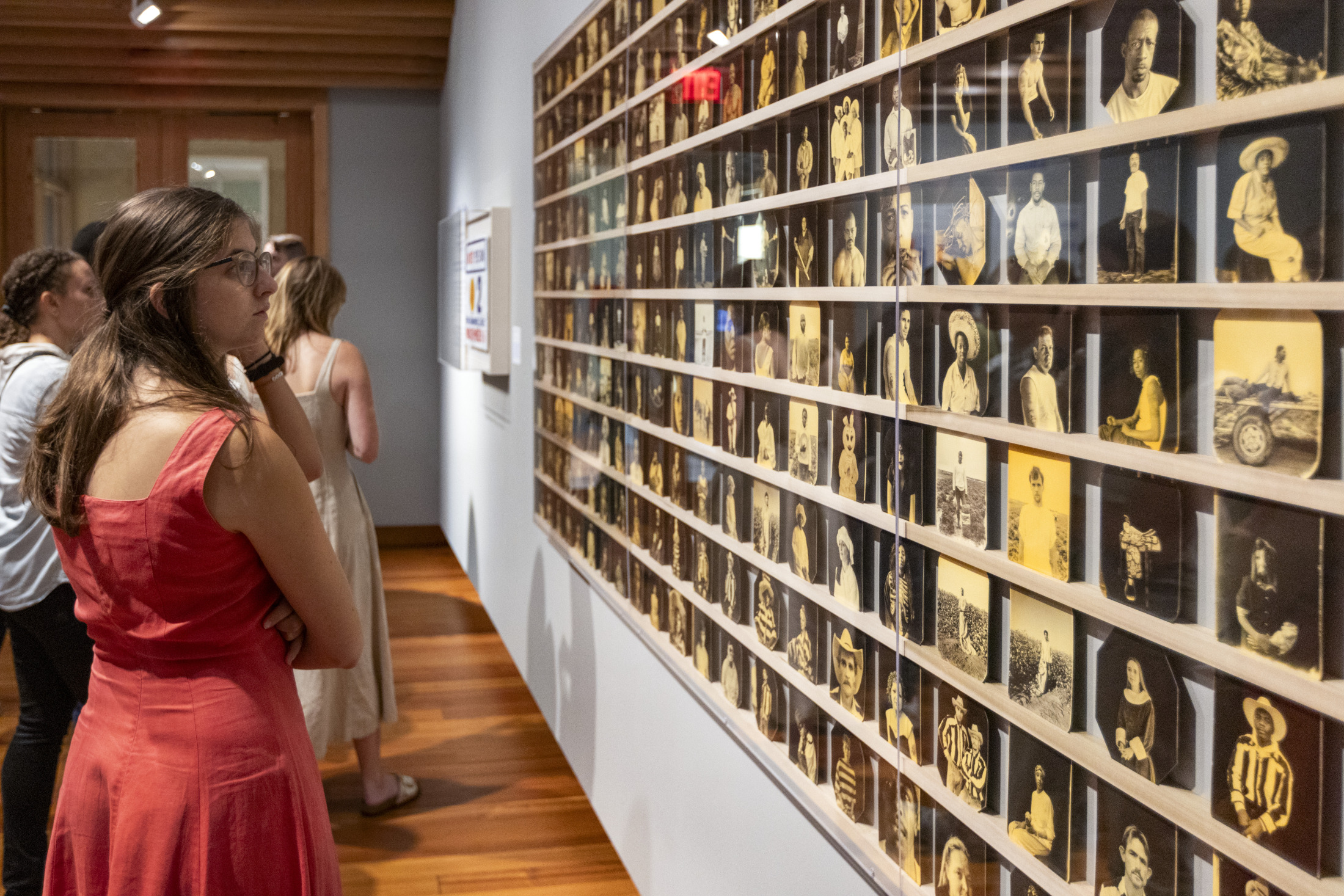 A woman looks at an array of printed photographs of incarcerated individuals at the Historic New Orleans Collection's "Captive State" exhibition.