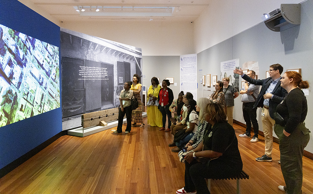 Museum visitors watch A Deliberate Retreat: New Orleans’s Shifting Jails in HNOC's Captive State exhibition.