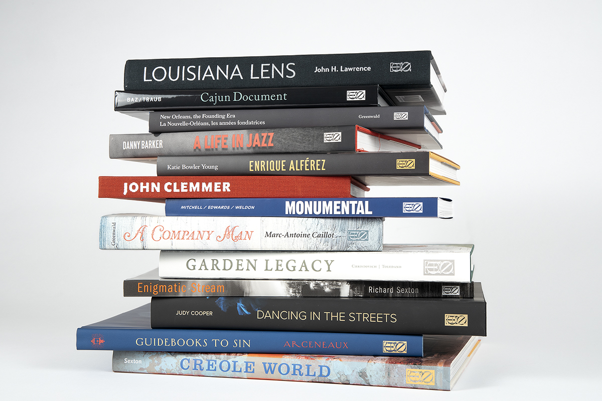 A stack of books with various titles, including Louisiana Lens by John H. Lawrence, A Life in Jazz by Danny Barker, Garden Legacy, and Creole World by Richard Sexton, arranged neatly against a plain background.