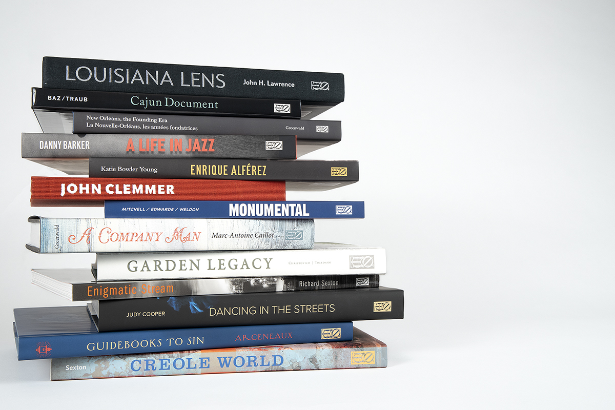 A stack of books against a plain background. Titles include Louisiana Lens, A Life in Jazz, Monumental, Garden Legacy, Enigmatic Stream, Dancing in the Streets, and Creole World, among others.