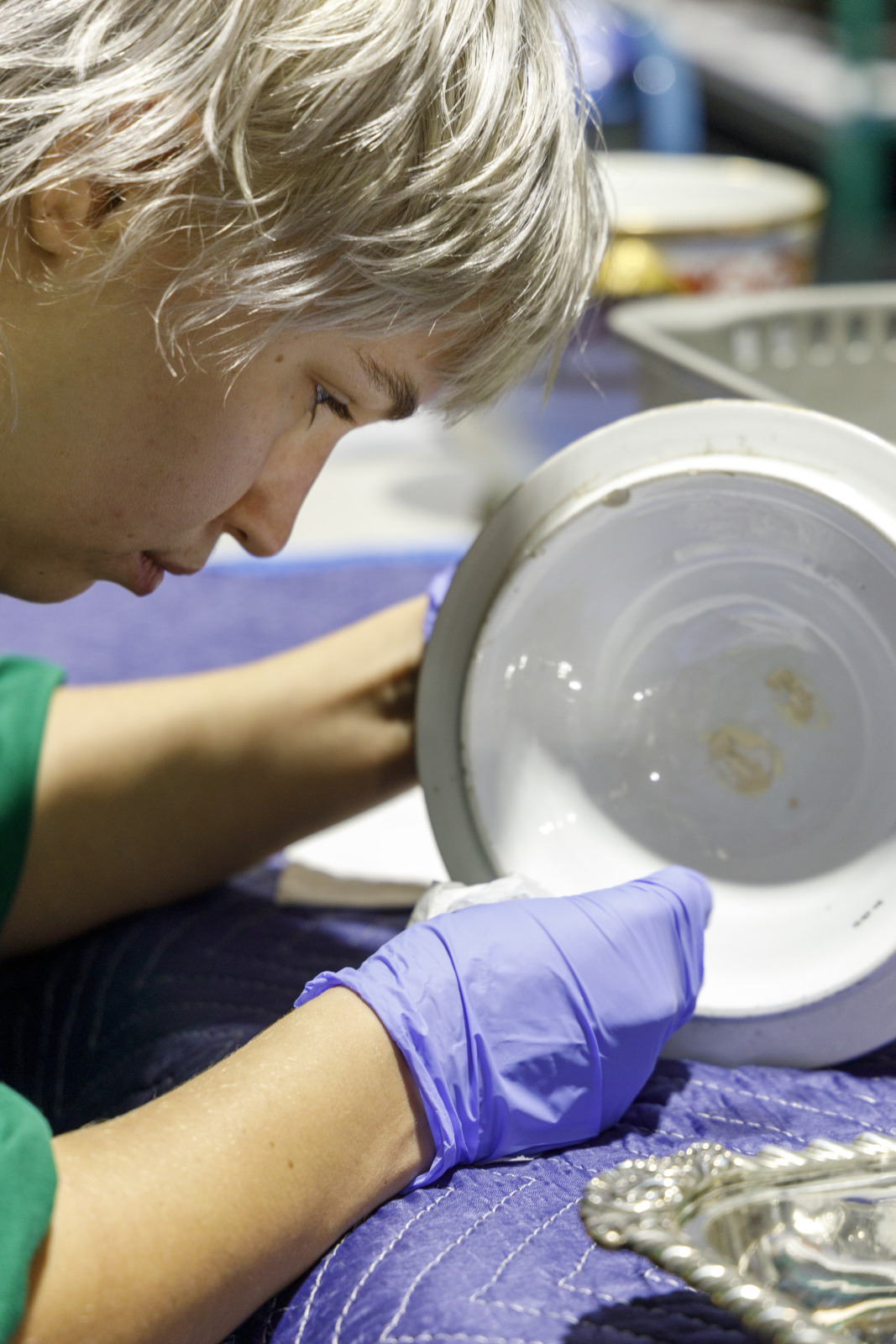 Kylie Hewitt carefully cleans the lid of a porcelain urn.