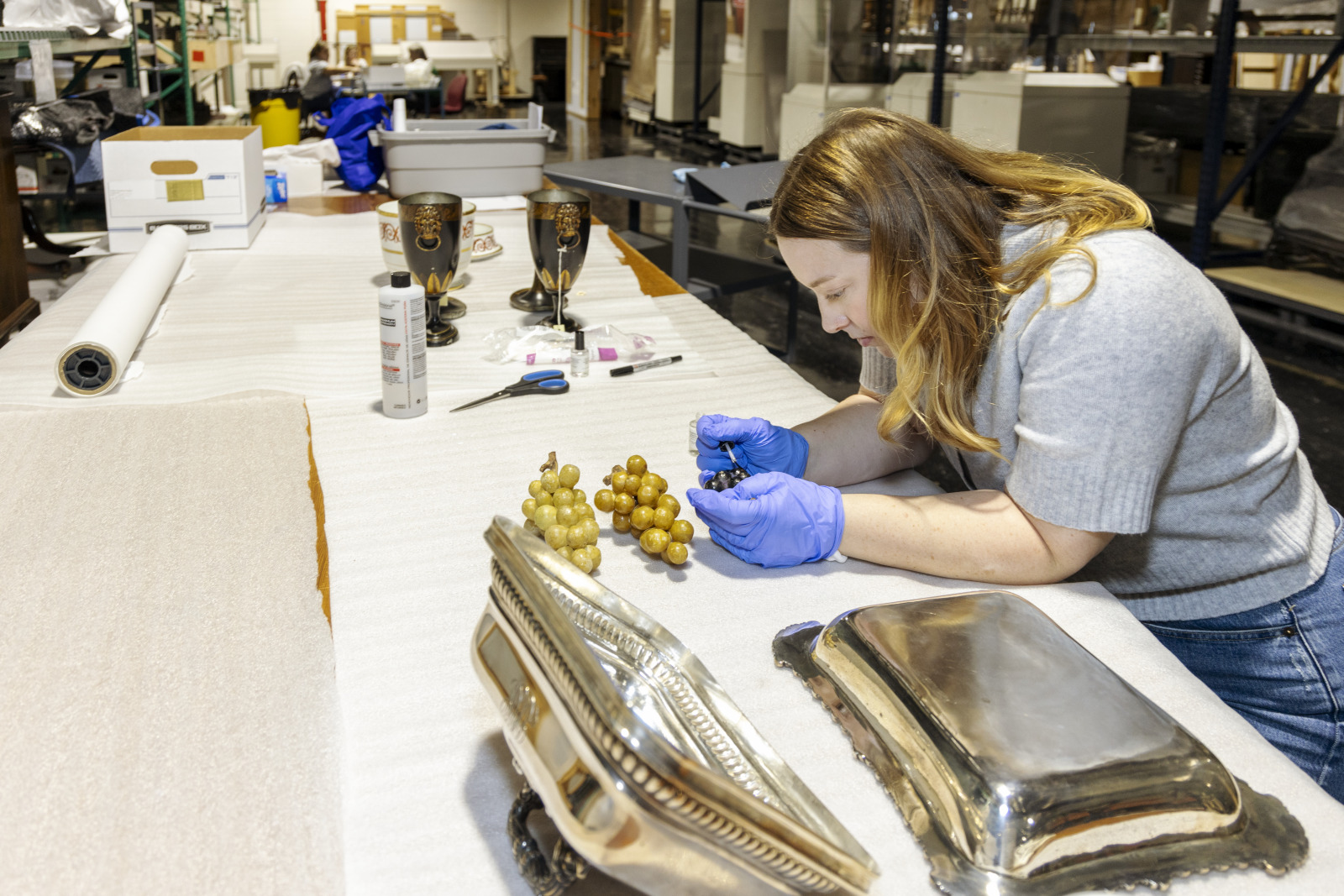 Kristin Hebert Veit adds museum numbers to a set of stone grapes.