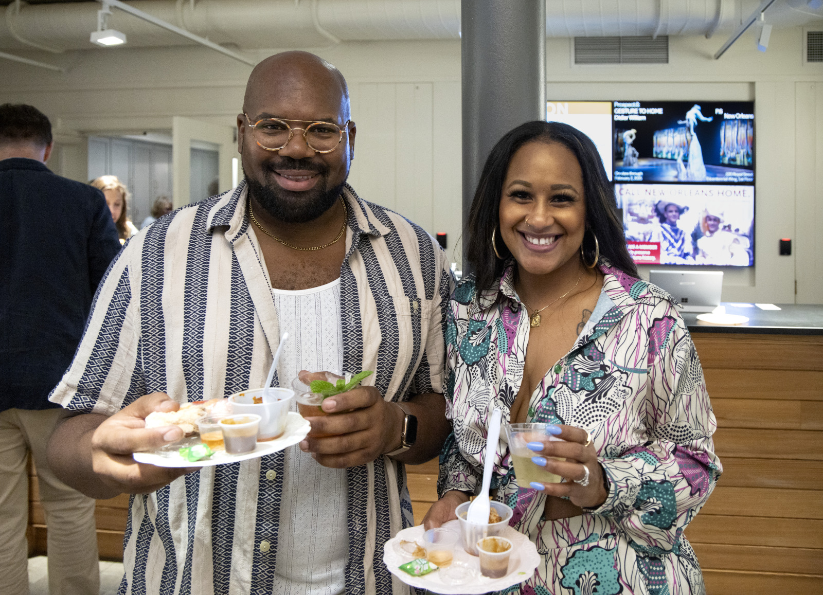 Two smiling guests hold plates of food and glasses of wine at HNOC's annual Food Forum.