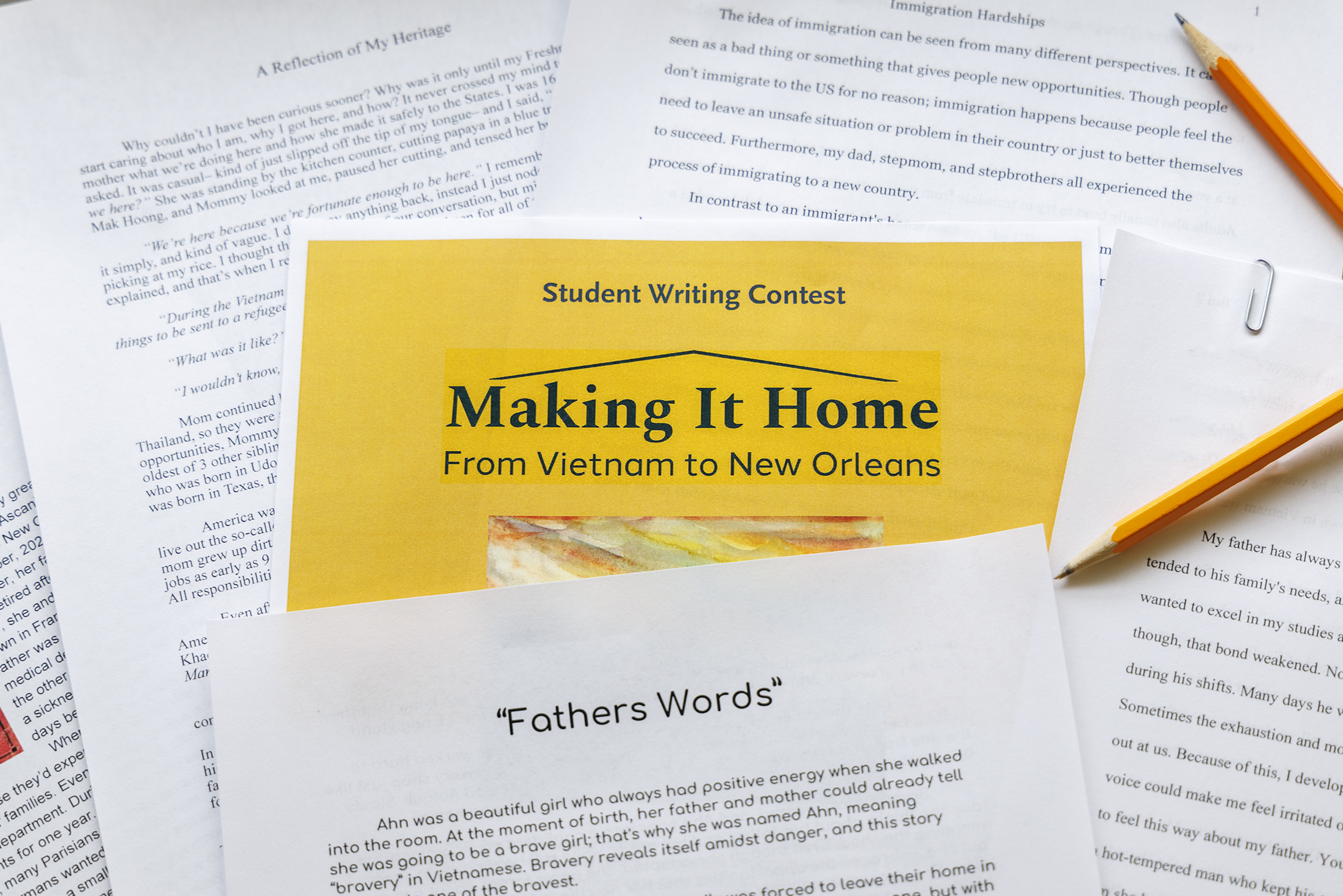 A photo of printed entries lying on a table, from HNOC's 2025 Student Writing Contest entitled "Making It Home".