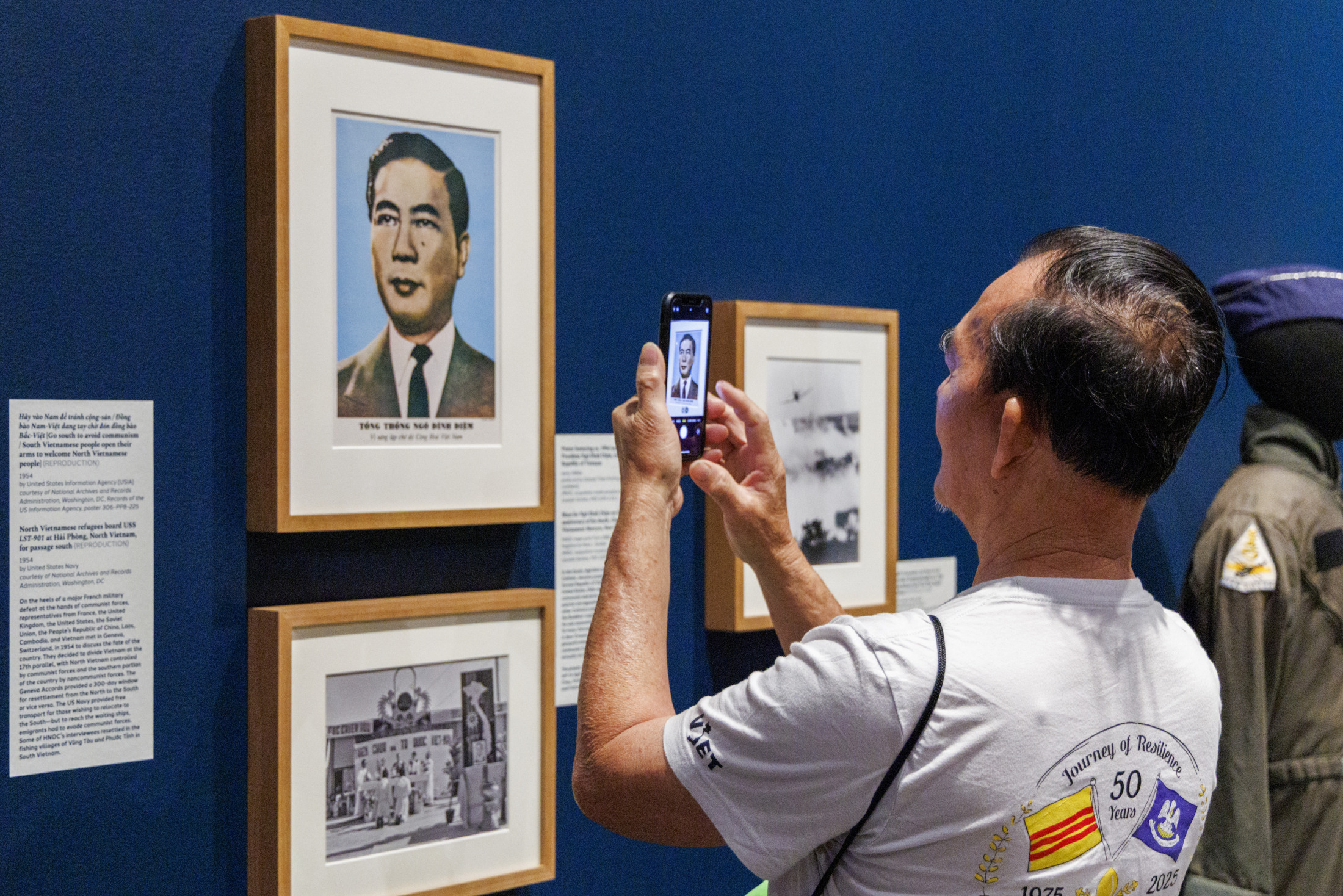 A man takes a picture of a photograph featured in an HNOC exhibition.