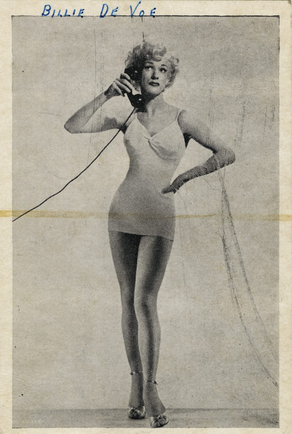Drag performer Billie De Voe poses in a short dress holding a telephone .