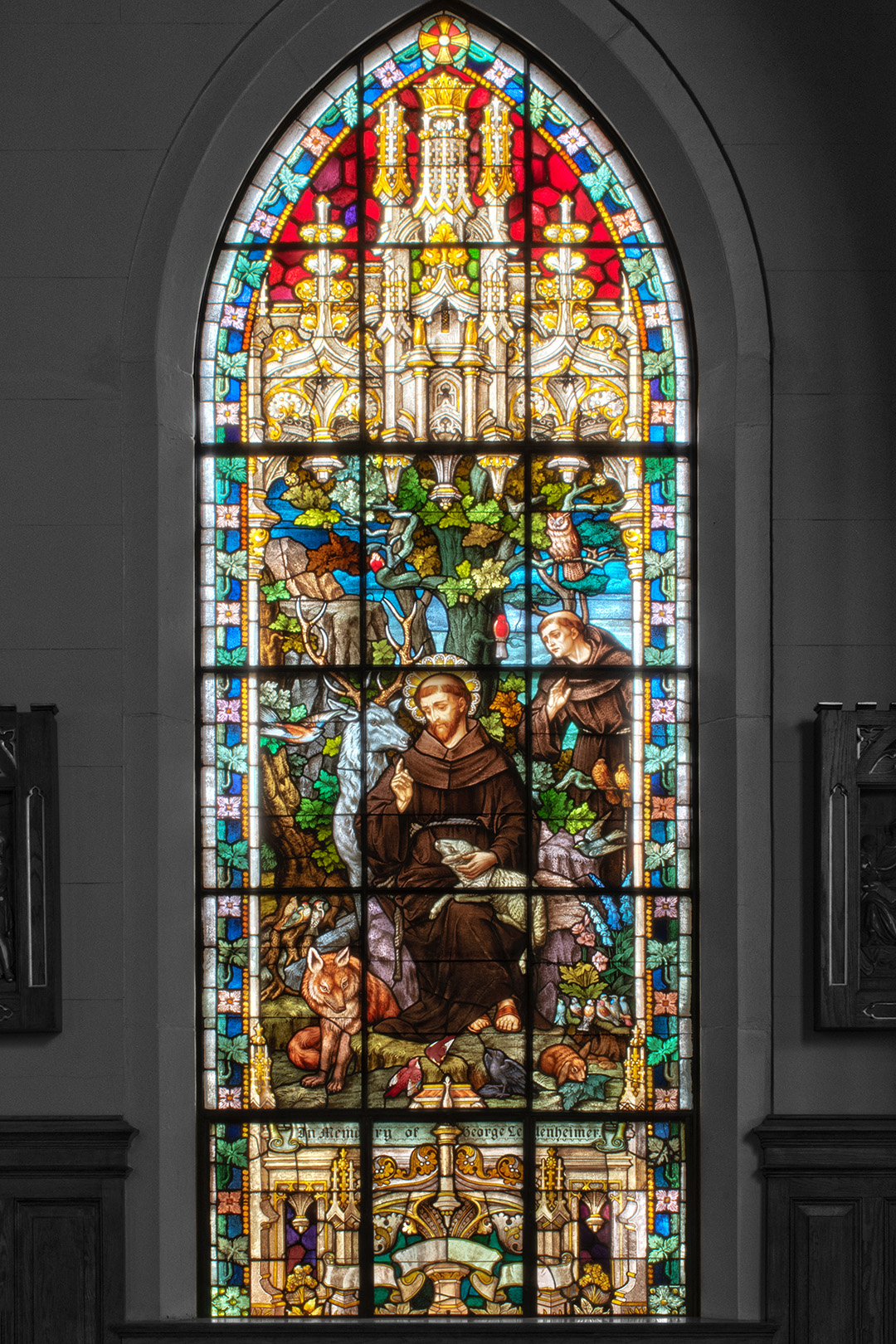 Photo of a stained glass window at St. Francis of Assisi Catholic Church depicting St. Francis surrounded by animals and with a lamb in his lap.