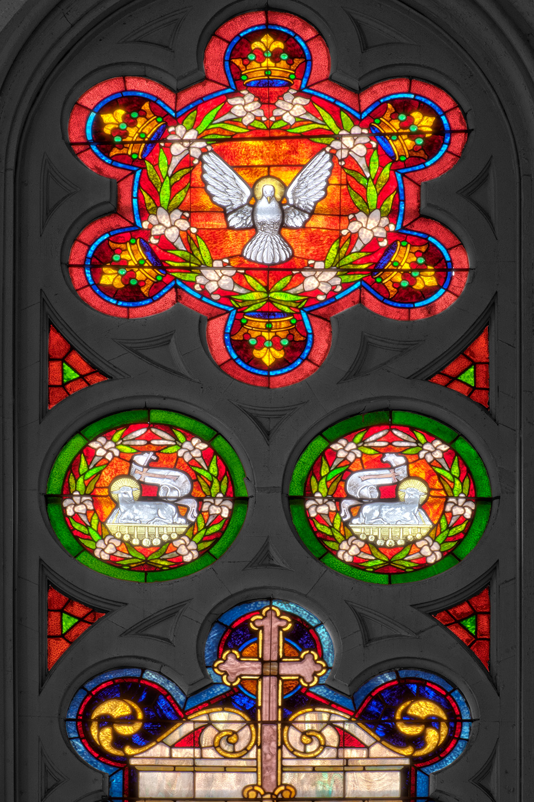 Photograph of a staind glass window depicting a dove, located at Saints Peter and Paul Catholic Church (now Hotel Peter and Paul).