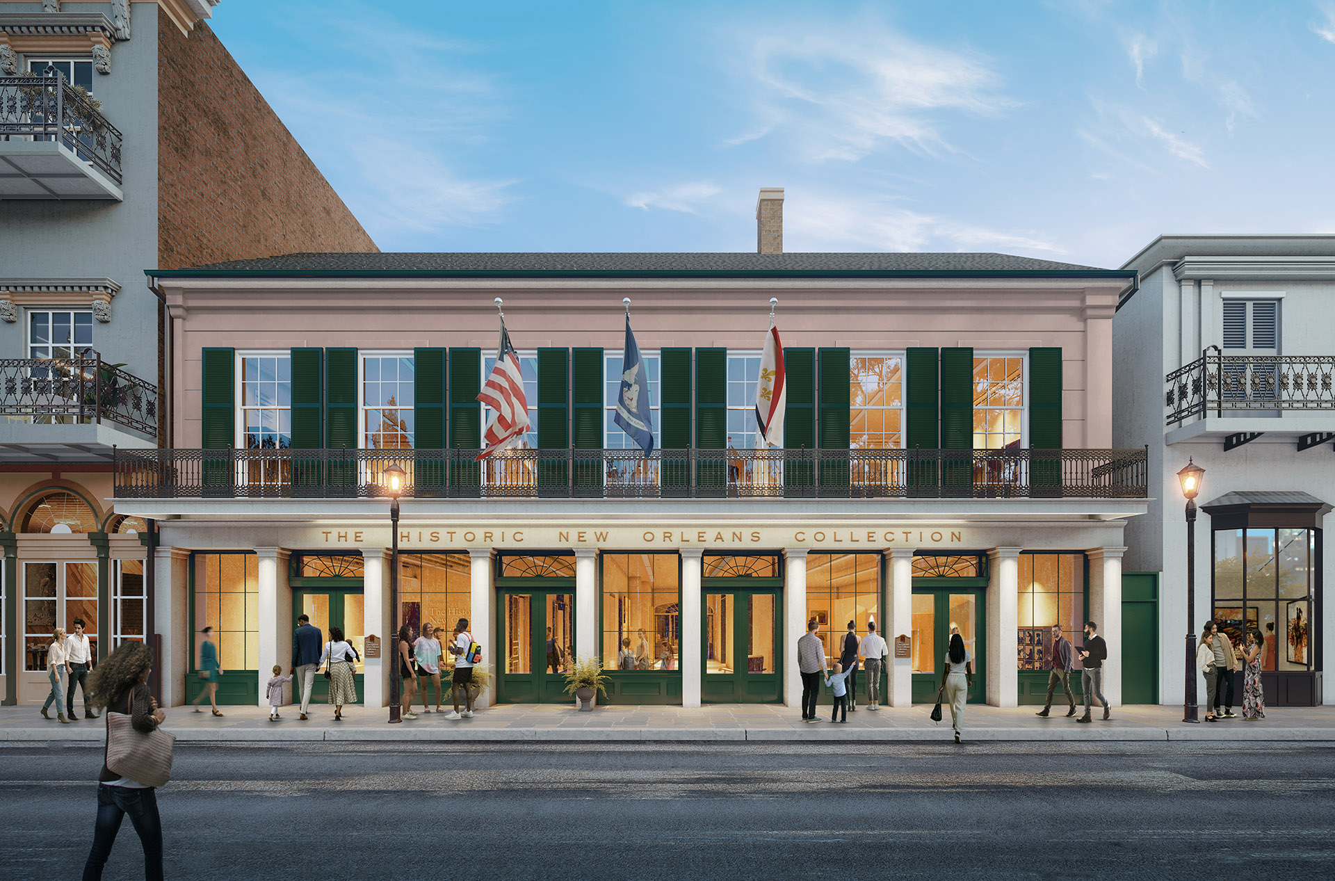 A historic building in New Orleans features a pink facade with green shutters. Three flags fly above the entrance. People walk and stand in groups outside, and a person rides a bicycle past on the street. The sky is clear and blue.