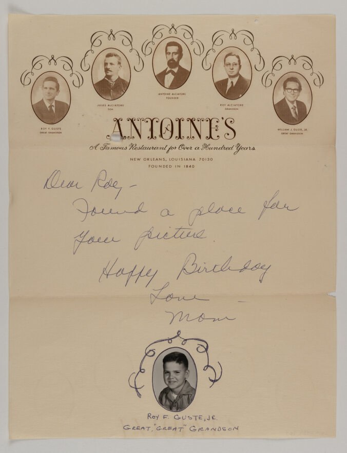 A vintage menu from Antoines Restaurant in New Orleans, with portraits of notable figures at the top. Below, a handwritten birthday message reads, Dear Roy, found a place for your picture. Happy Birthday. Love, Mom, with a photo of Roy F. Guste, Jr.