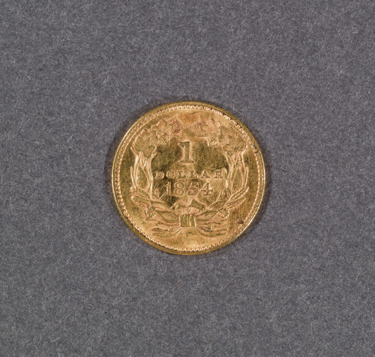 A gold coin from 1854 featuring a 1 Dollar inscription, encircled by a wreath and topped with the date. The coin is set against a gray background.